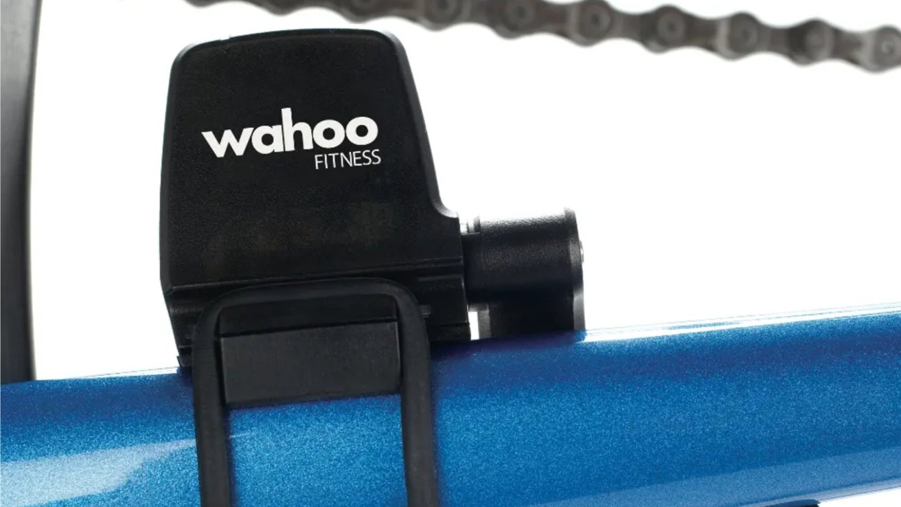 Black Wahoo Fitness device attached to a metallic blue surface with a blurred bike chain in the background.